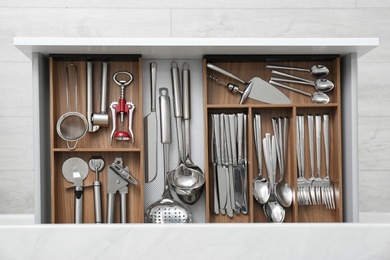 Photo of Open drawer with different utensils and cutlery in kitchen, top view