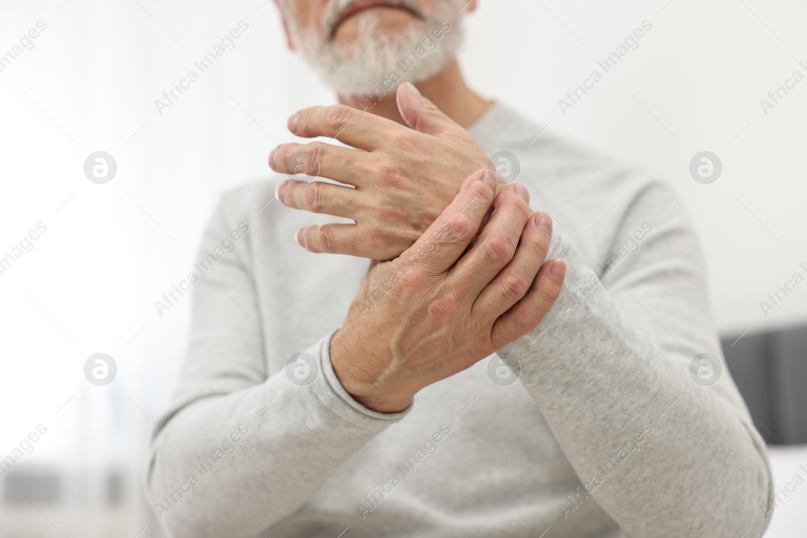 Photo of Arthritis symptoms. Man suffering from pain in wrist at home, closeup