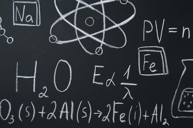 Photo of Different chemical formulas written with chalk on blackboard, closeup