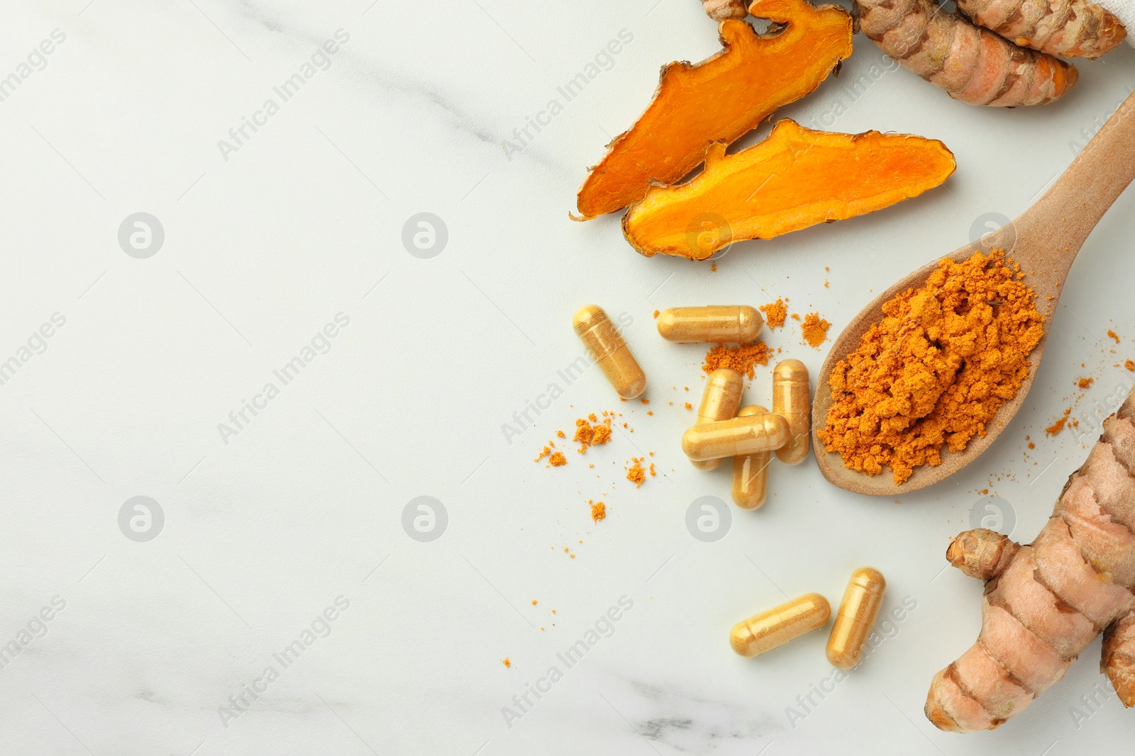 Photo of Aromatic turmeric powder, pills and raw roots on white marble table, flat lay. Space for text