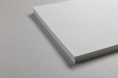 Photo of Blank paper sheets on grey textured table, closeup. Mockup for design