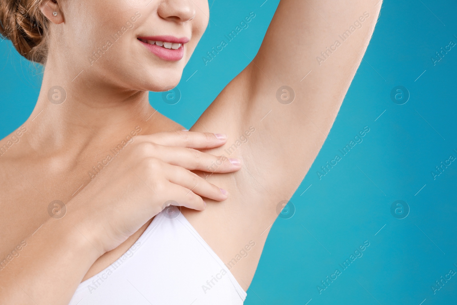 Photo of Young woman with smooth clean armpit on teal background, closeup. Using deodorant