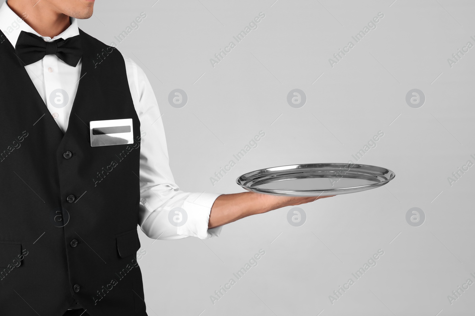 Photo of Waiter holding metal tray on grey background