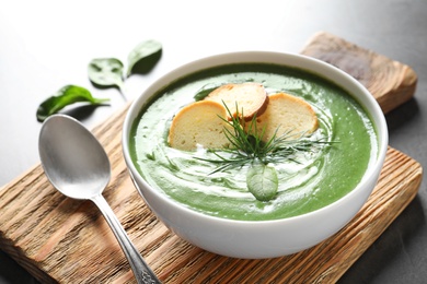 Photo of Fresh vegetable detox soup made of spinach with croutons in dish served on table