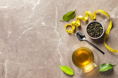 Flat lay composition with herbal diet tea and measuring tape on brown marble table, space for text. Weight loss concept