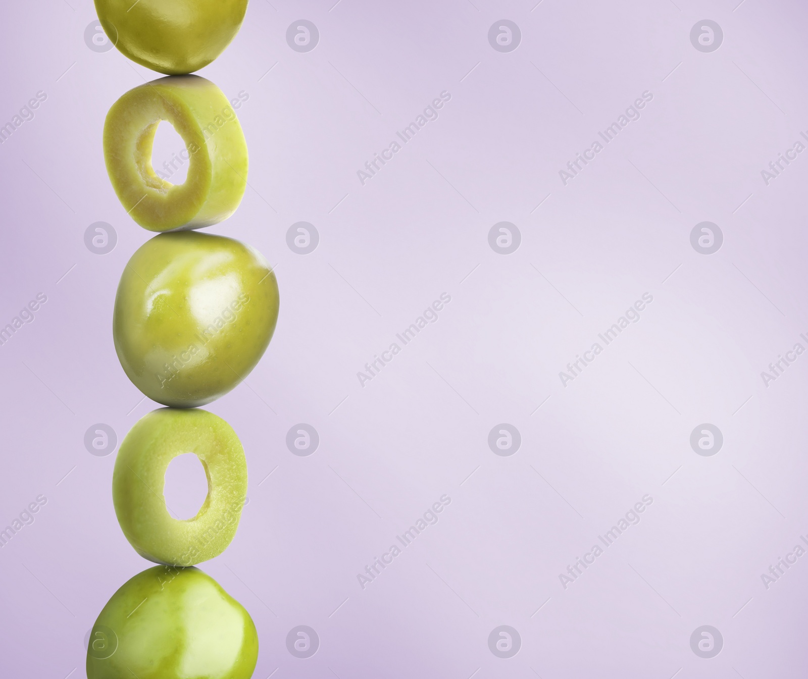 Image of Cut and whole green olives on light violet gradient background, space for text