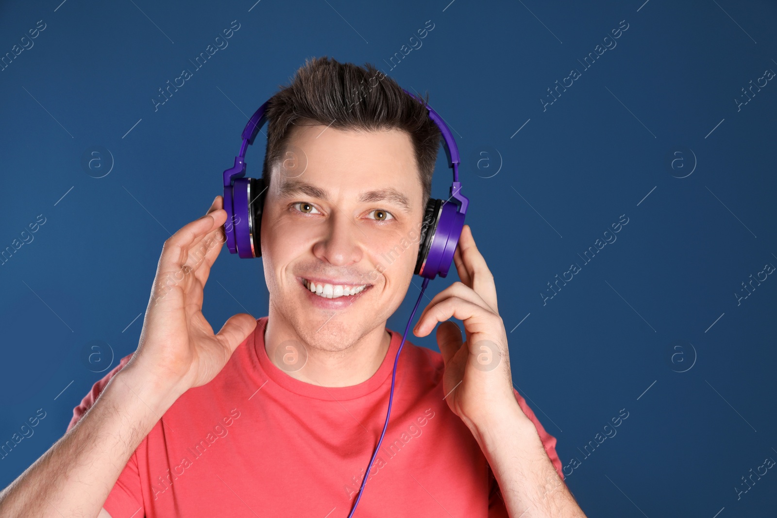 Photo of Man enjoying music in headphones on color background