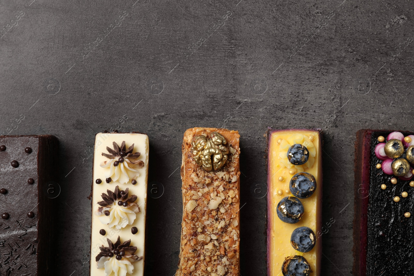 Photo of Different delicious cakes on grey table, flat lay. Space for text