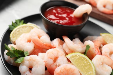 Tasty boiled shrimps with cocktail sauce, parsley and lime on light grey table, closeup