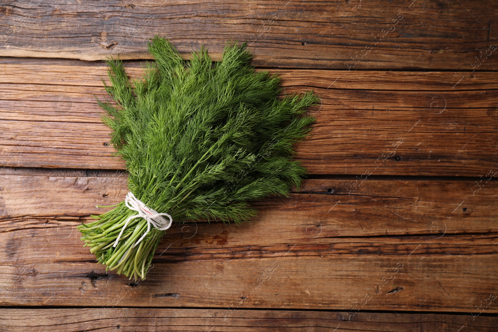 Photo of Bunch of fresh green dill on wooden table, top view. Space for text