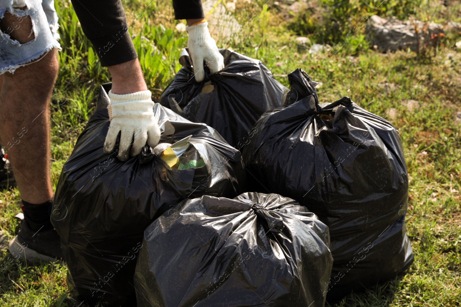 Photo of Man with trash bags full of garbage outdoors, closeup. Environmental Pollution concept