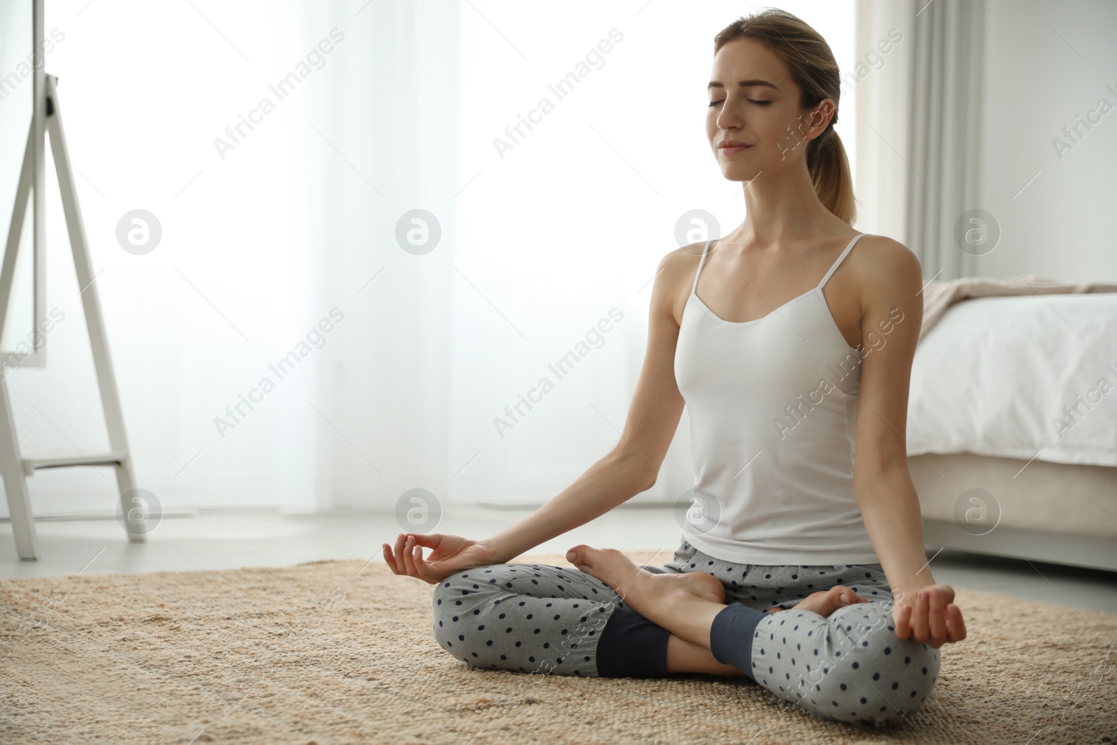 Photo of Young woman meditating on floor at home. Morning fitness