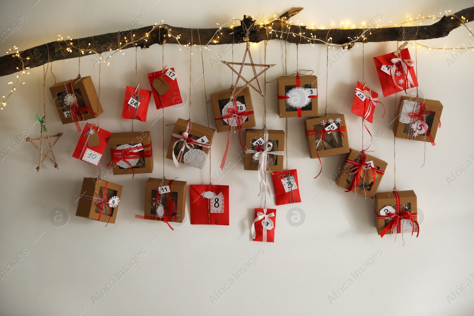 Photo of Handmade Advent calendar with gifts hanging on white wall. Christmas season