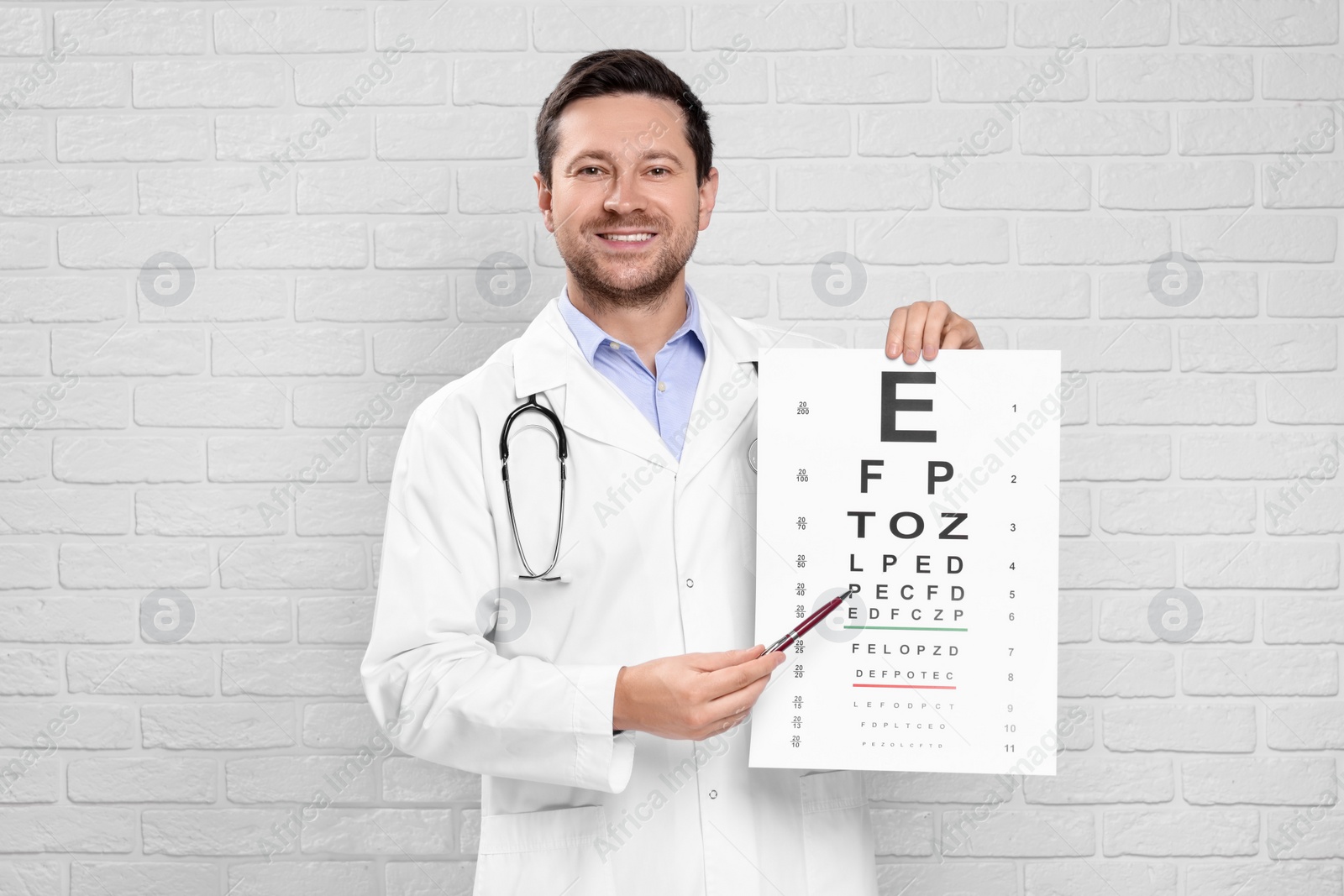 Photo of Ophthalmologist pointing at vision test chart near white brick wall