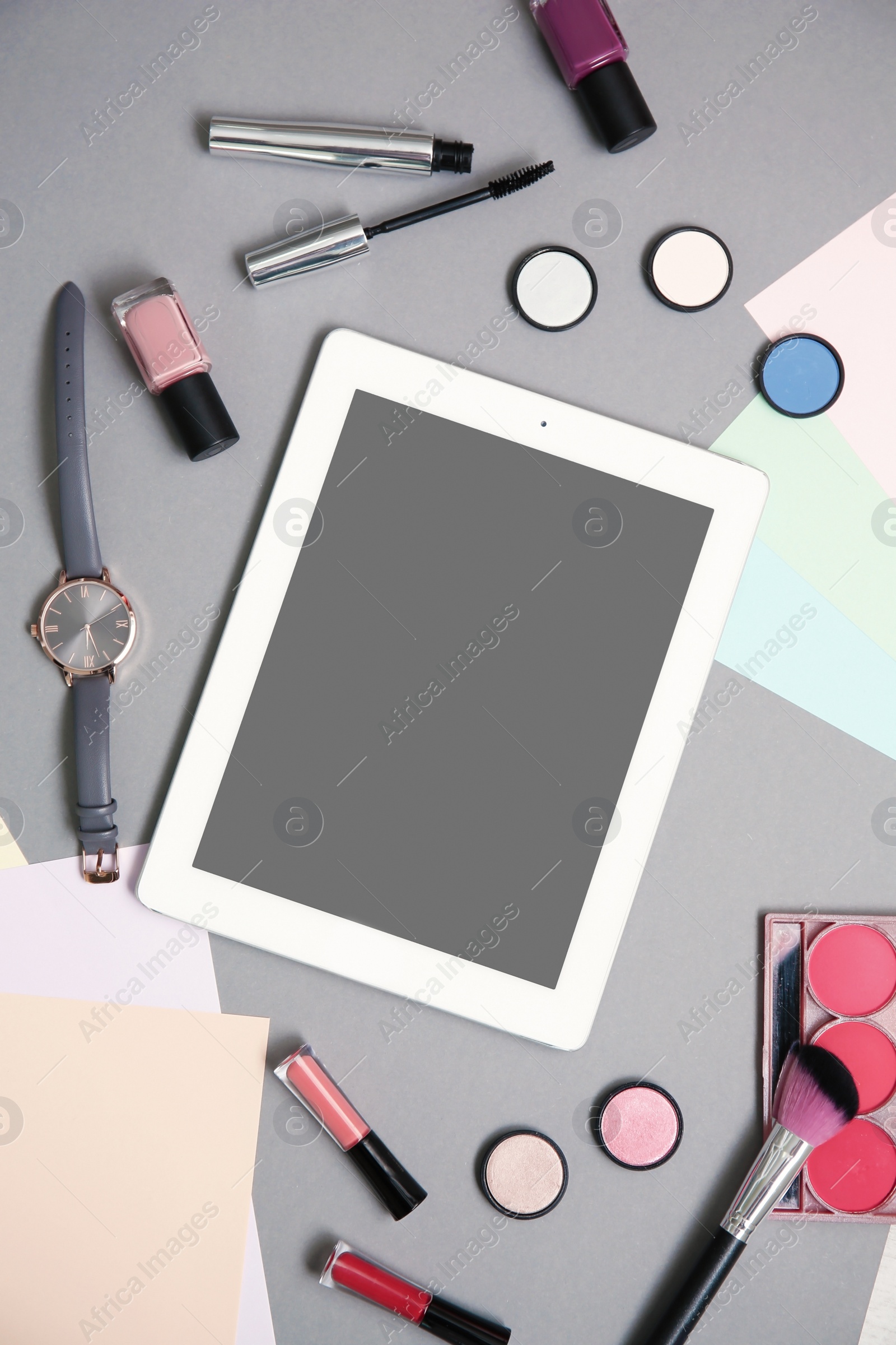 Photo of Flat lay composition with tablet and makeup products for woman on grey background