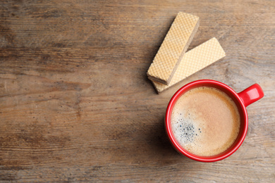 Breakfast with delicious wafers and coffee on wooden table, flat lay. Space for text