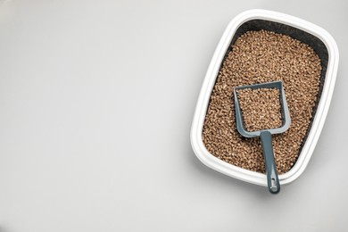 Photo of Cat litter tray with filler and scoop on light background, top view. Space for text