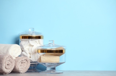 Photo of Composition of glass jar with cotton pads on table near blue wall. Space for text