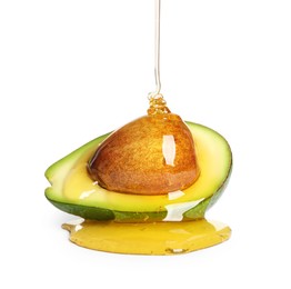 Photo of Pouring essential oil onto cut avocado on white background