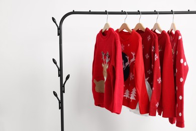 Photo of Rack with different Christmas sweaters on white background