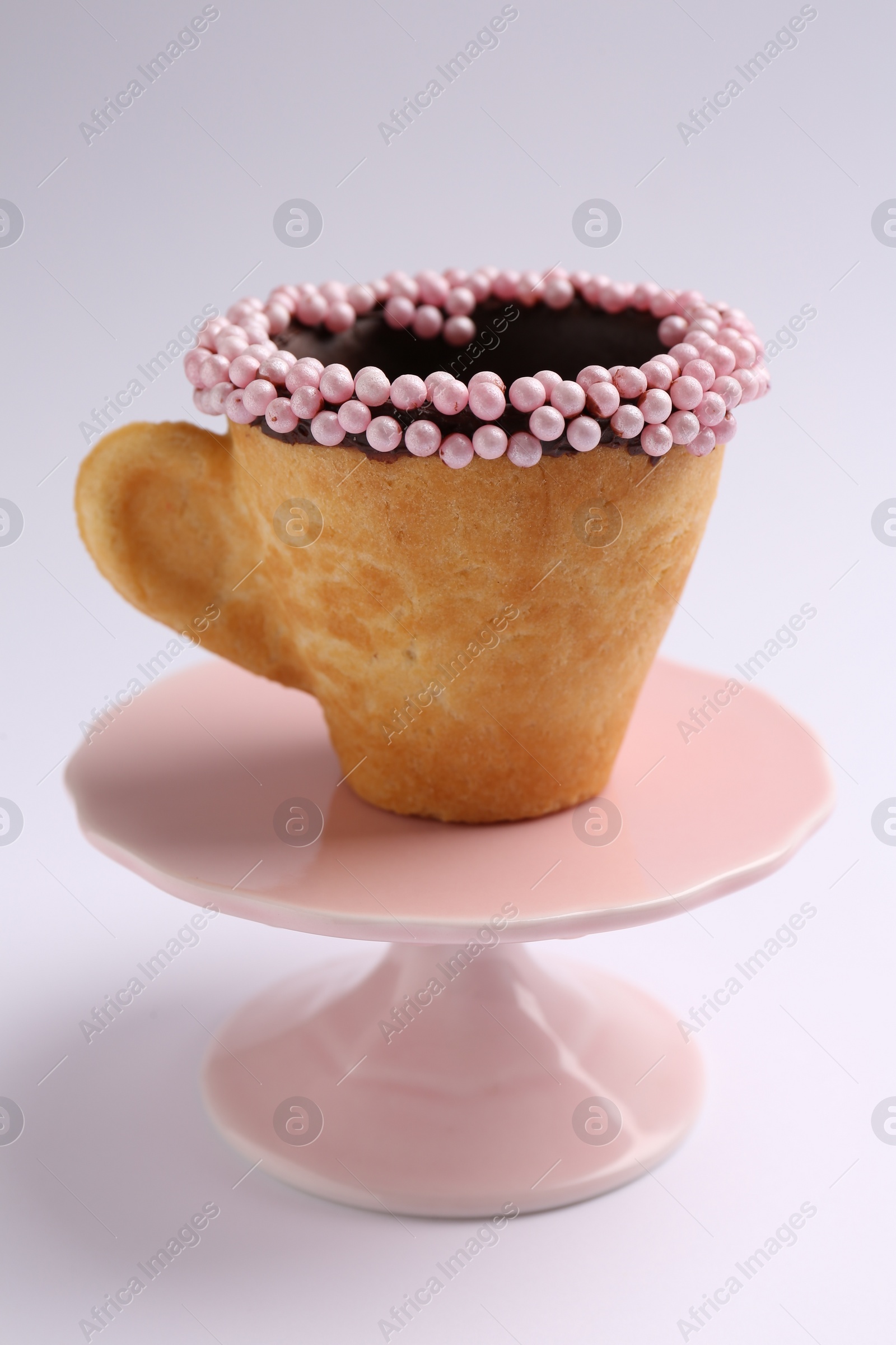 Photo of Delicious edible biscuit cup decorated with sprinkles on white background