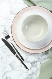 Photo of Clean plates, bowl and cutlery on white marble table, flat lay