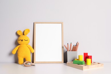 Photo of Empty square frame, stationery and different toys on white table