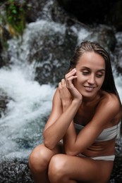Beautiful young woman in light blue bikini near mountain stream outdoors. Space for text