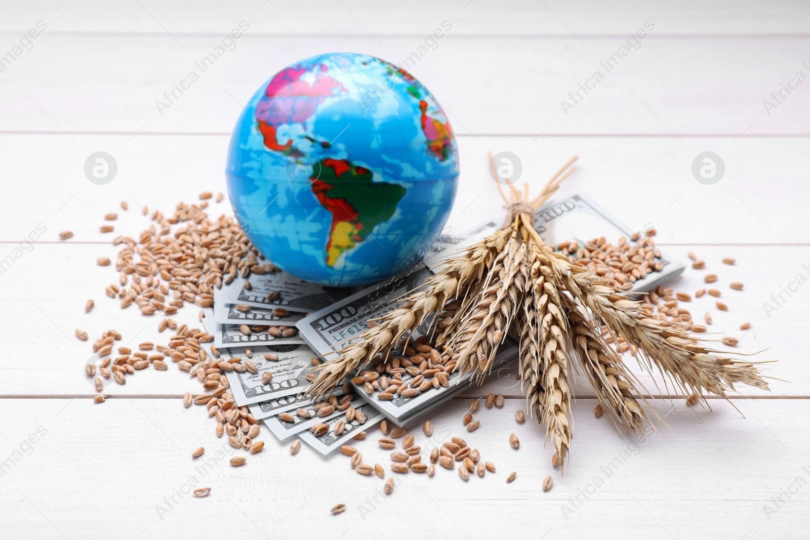 Photo of Globe, ears of wheat and banknotes on white wooden table. Import and export concept
