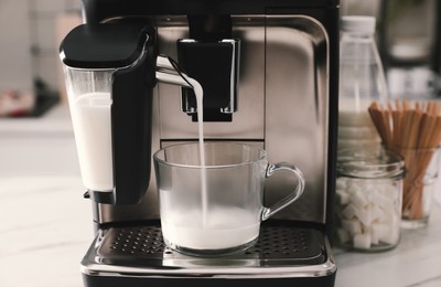Modern coffee machine with cup in office kitchen, closeup