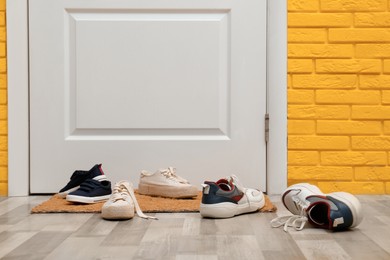 Photo of Stylish shoes and mat near door in hallway