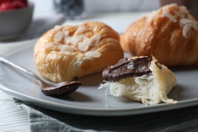 Delicious croissants with almond flakes and chocolate on table, closeup