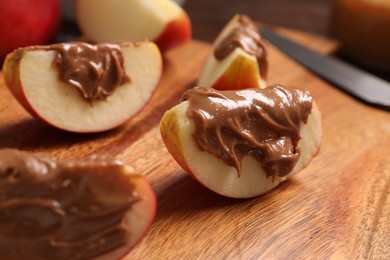 Photo of Slices of fresh apple with nut butter on wooden board, closeup