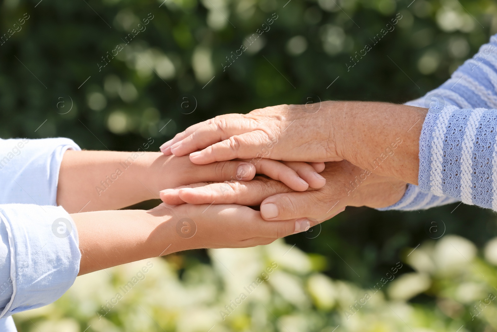 Photo of Helping hands on blurred background, closeup. Elderly care concept