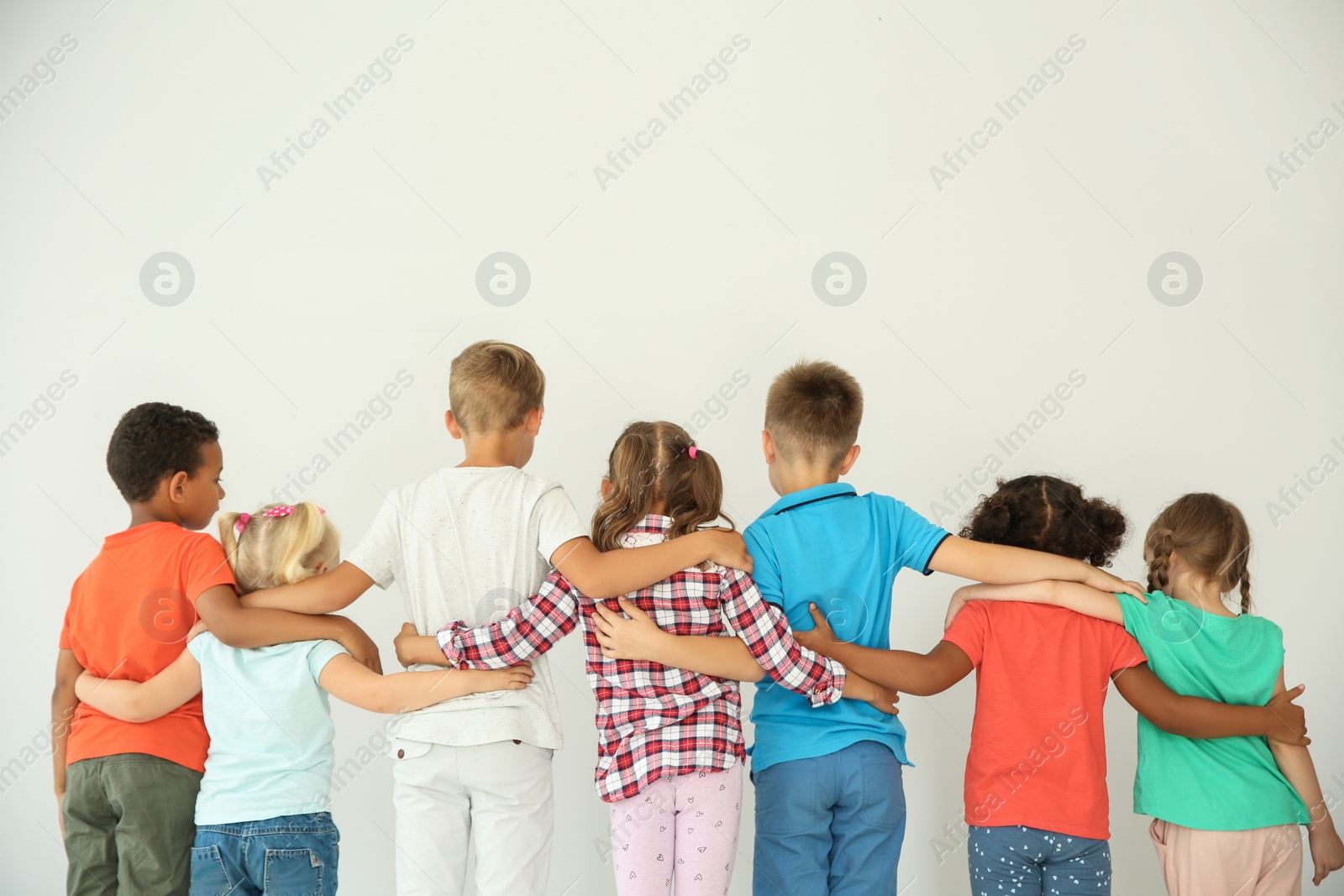 Photo of Little children hugging each other with hands on light background. Unity concept