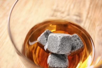 Glass with liquor and whiskey stones on table, closeup