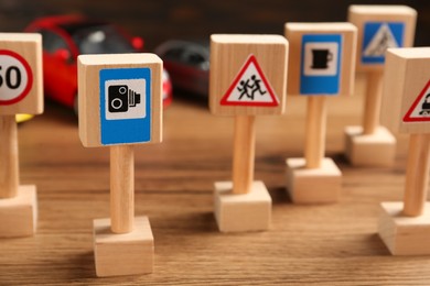 Photo of Many different miniature road signs on wooden table, closeup. Driving school