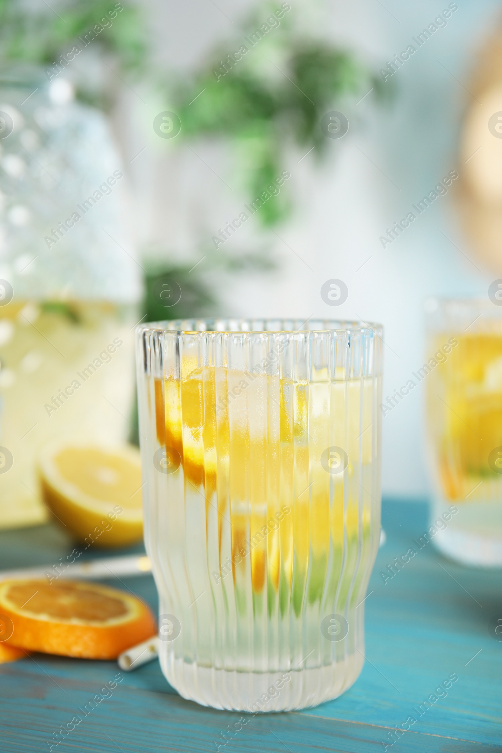 Photo of Delicious refreshing lemonade with orange slices on light blue wooden table