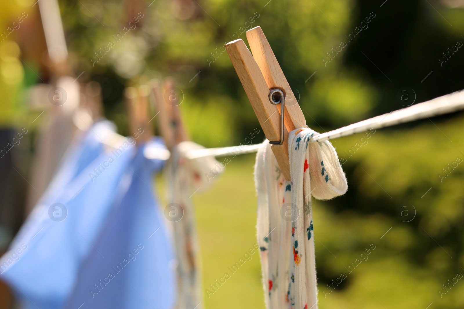 Photo of Clean clothes drying in garden, closeup. Focus on clothespin