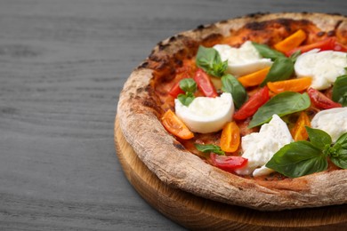 Delicious pizza with burrata cheese, tomatoes and basil on grey wooden table, closeup. Space for text