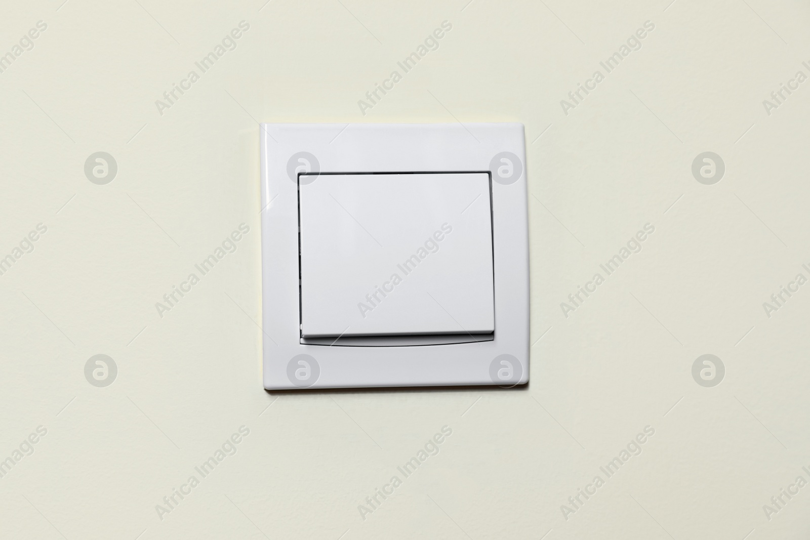 Photo of Modern plastic light switch on white wall, closeup