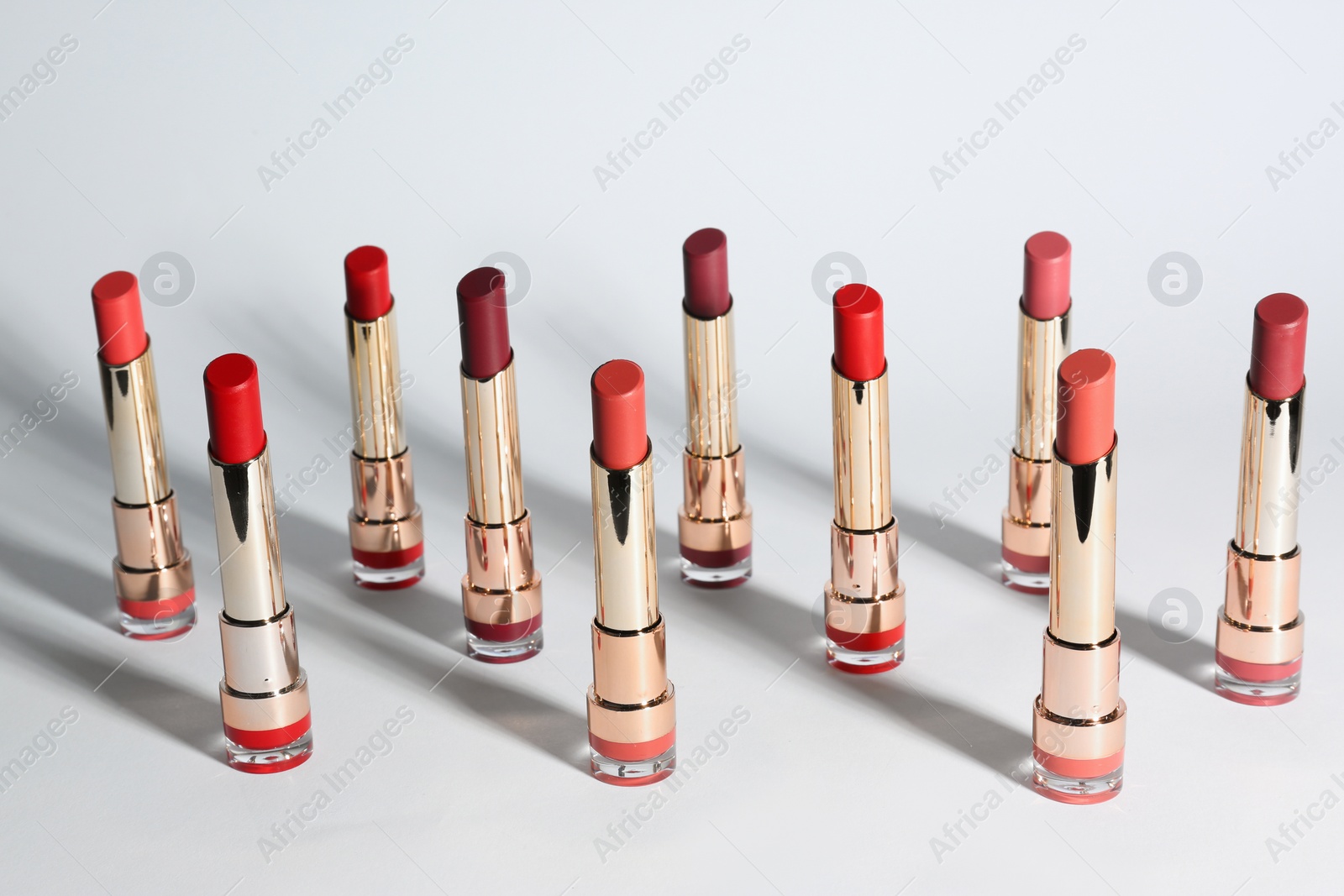 Photo of Set of bright lipsticks in gold tubes on white background