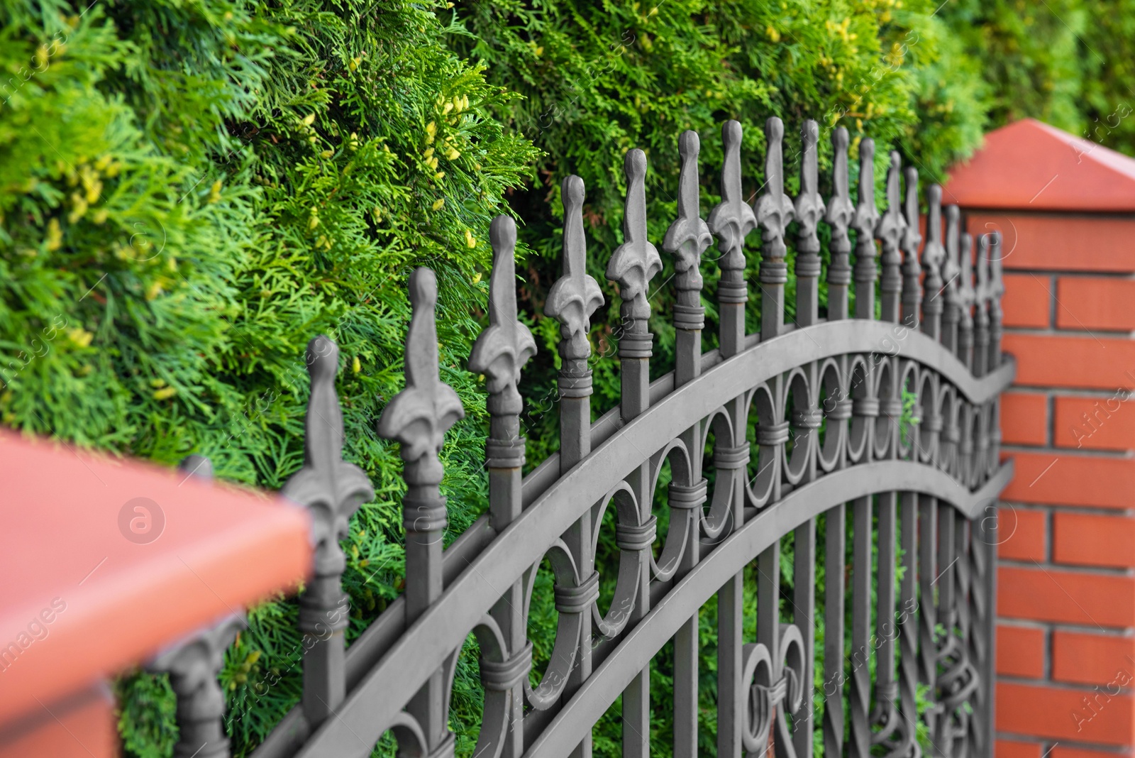 Photo of Beautiful brick fence with iron railing outdoors, closeup