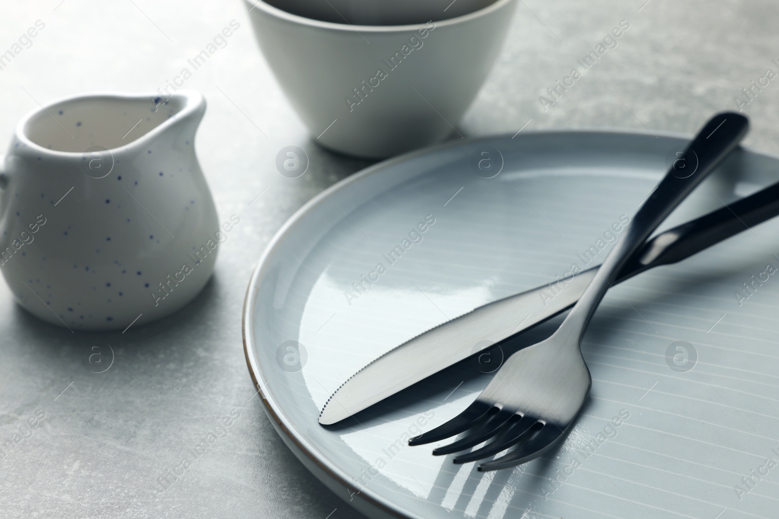 Photo of Stylish empty dishware and cutlery on light grey table, closeup