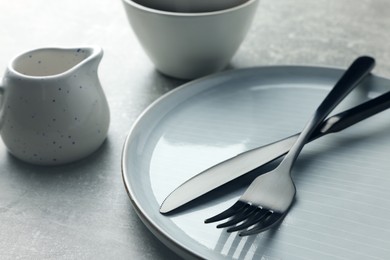 Photo of Stylish empty dishware and cutlery on light grey table, closeup