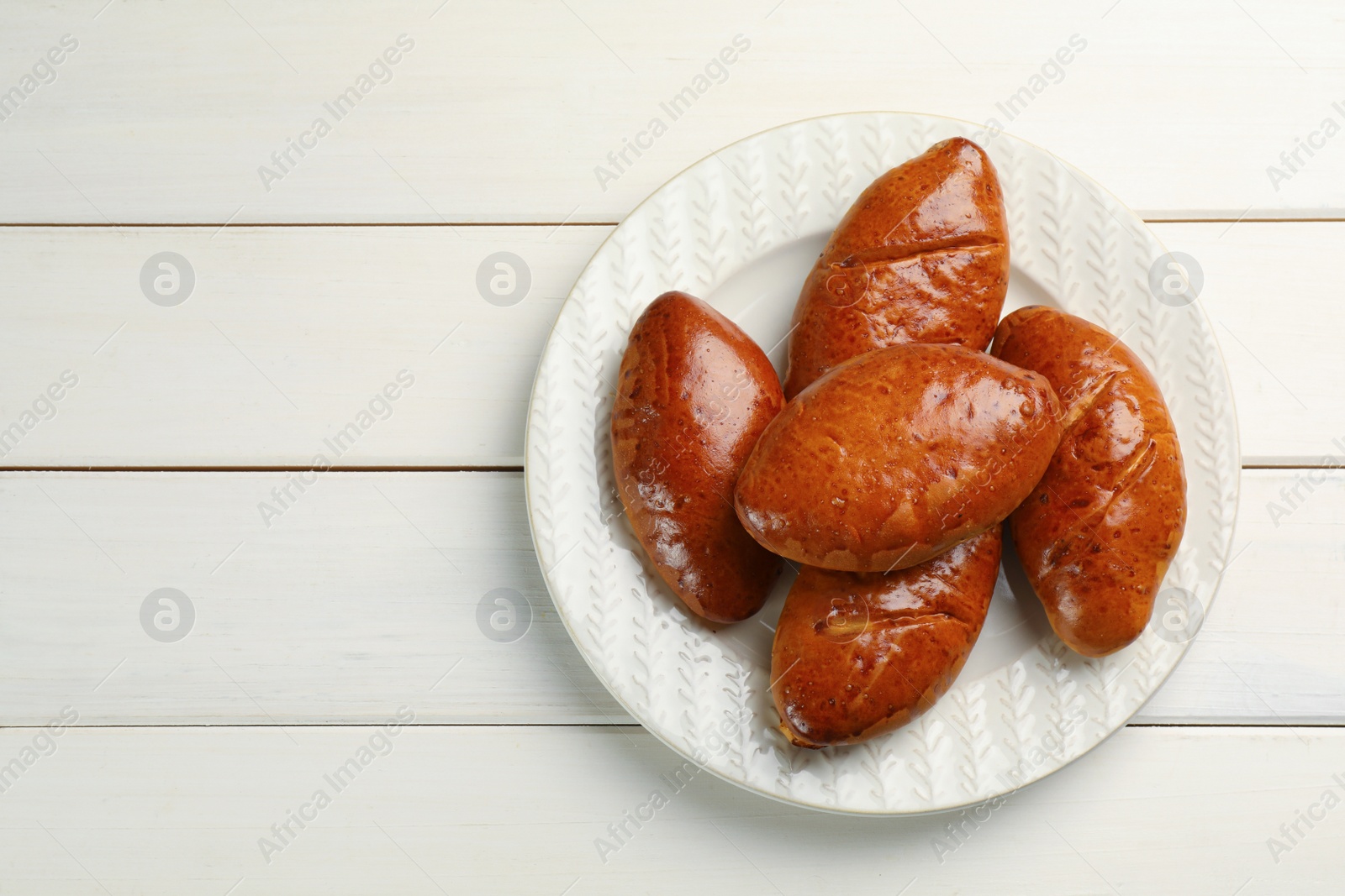 Photo of Delicious baked patties on white wooden table, top view. Space for text