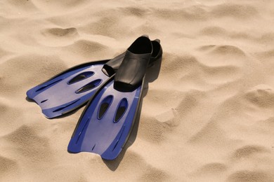 Photo of Pair of blue flippers on sand. Space for text