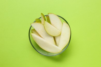 Photo of Sliced fresh pear in bowl on green background, top view. Finger food