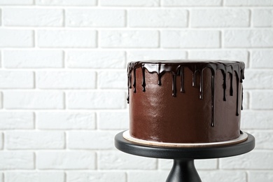 Photo of Freshly made delicious chocolate cake against white brick wall. Space for text