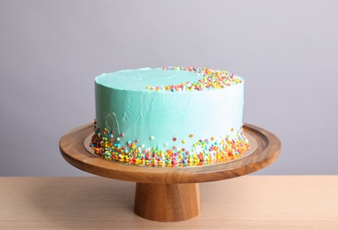 Photo of Fresh delicious birthday cake on stand against light background